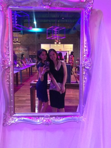 two women take a photo in front of mirror