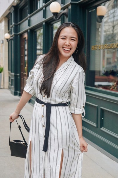 woman in white striped button up dress holding a black bag
